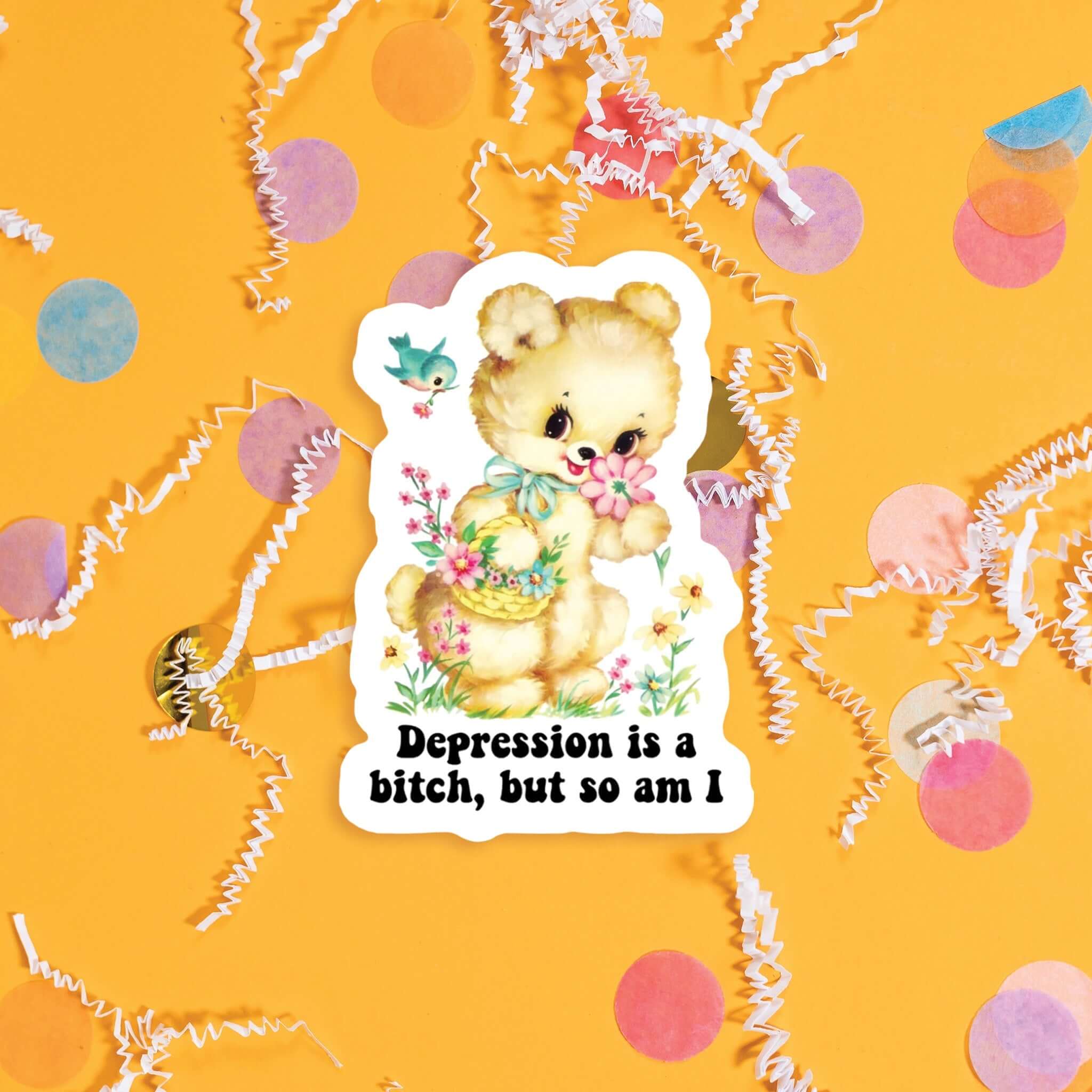 On a sunny mustard background sits a sticker with colorful confetti and white crinkle scattered around. This vintage sticker has an illustration of a darling tan bear holding a basket of flowers in one hand and smelling a flower with the other hand, and flowers and a bird. It says "Depression is a bitch, but so am I" in black, thick serif font. Approximately 3".