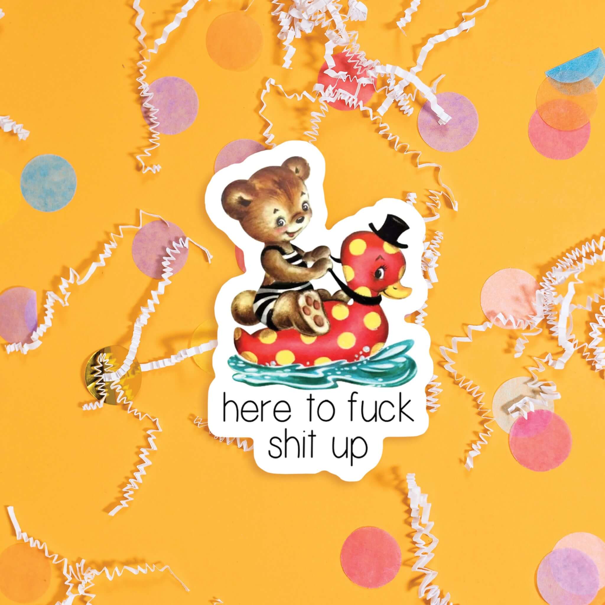 On a sunny mustard background sits a sticker with colorful confetti and white crinkle scattered around. This vintage sticker has an illustration of a cute brown bear sitting on a red rubber ducky floatie with yellow dots. The ducky has a black top hat on and the bear has a vintage black and white striped swimsuit on. It says "here to fuck shit up" in black, handdwritten skinny lettering. Approximately 3".