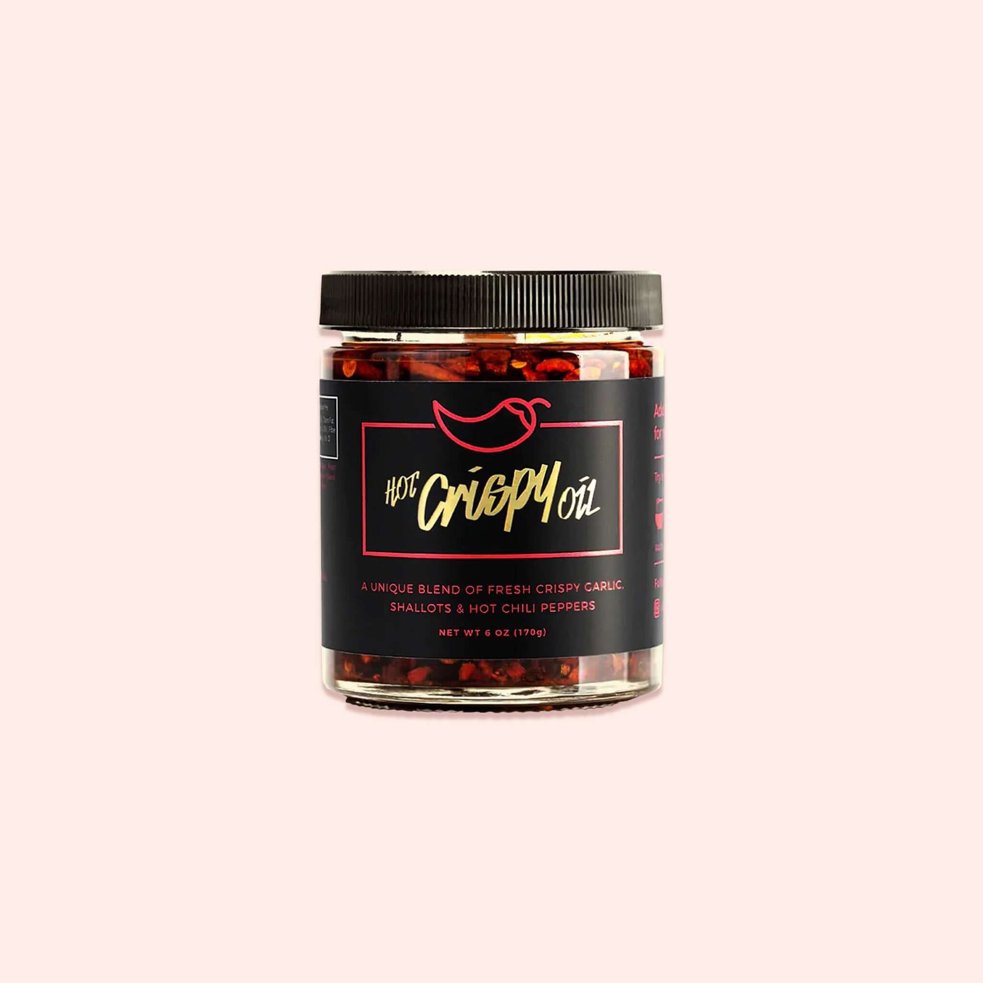 On a light pink background sits a jar with a black lid and black label. It has a red outlined box and a chili pepper above it. It says in gold "HOT Crispy Oil." It also says in red "A UNIQUE BLEND OF FRESH CRISPY GARLIC, SHALLOTS & HOT CHILI PEPPERS." NET WT 6 OZ (170G)