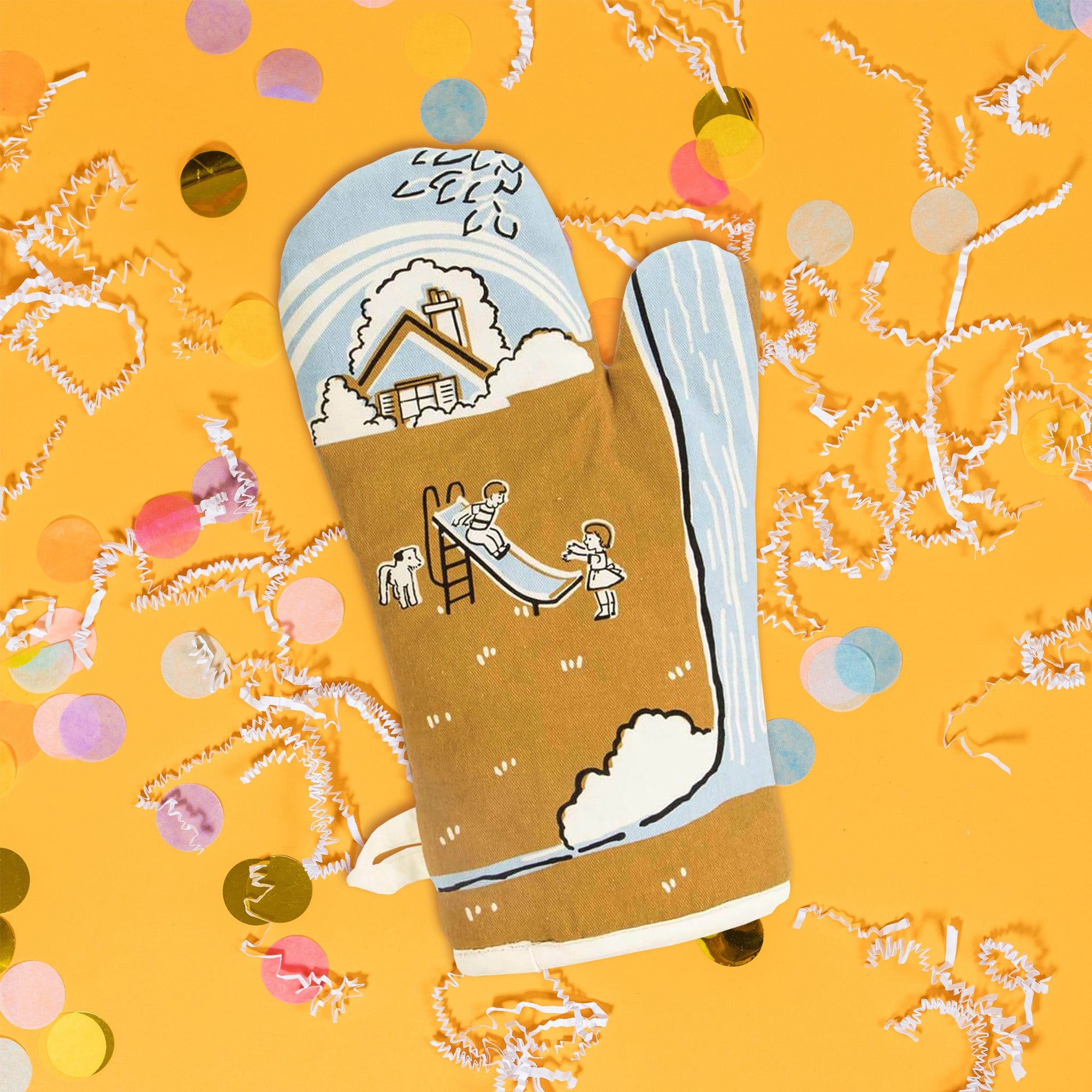 On a sunny mustard background sits an oven mitt with white crinkle and big, colorful confetti scattered around. The back of this light blue oven mitt has a vintage illustration of a house with trees, a dog and two children playing on a slide. The colors are light blue, gold, black, and white. At the top it says "I love my asshole kids." in black serif font.