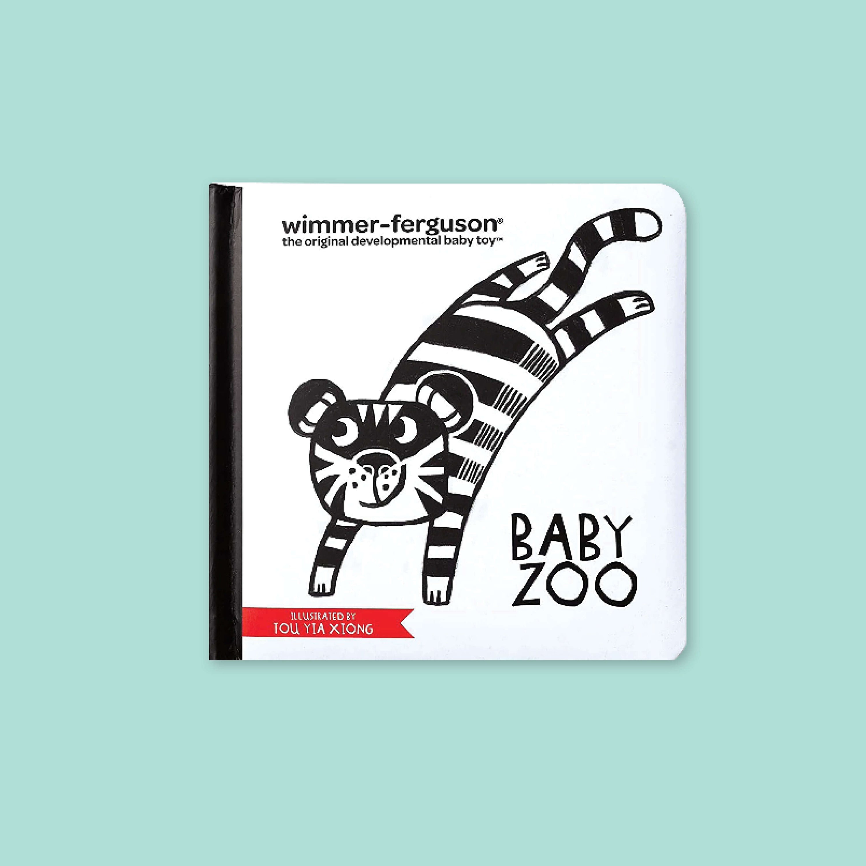 On a mint green background sits a white book with black spine. It has an illustration of a black and white tiger on the front and it says "BABY ZOO" in black, all caps handwritten lettering. It also says "ILLUSTRATED BY TOU YIA XIONG" in white, all caps handwritten lettering on a red banner. At the top left corner it says in black "wimmer-ferguson the original developmental baby toy" in block font.