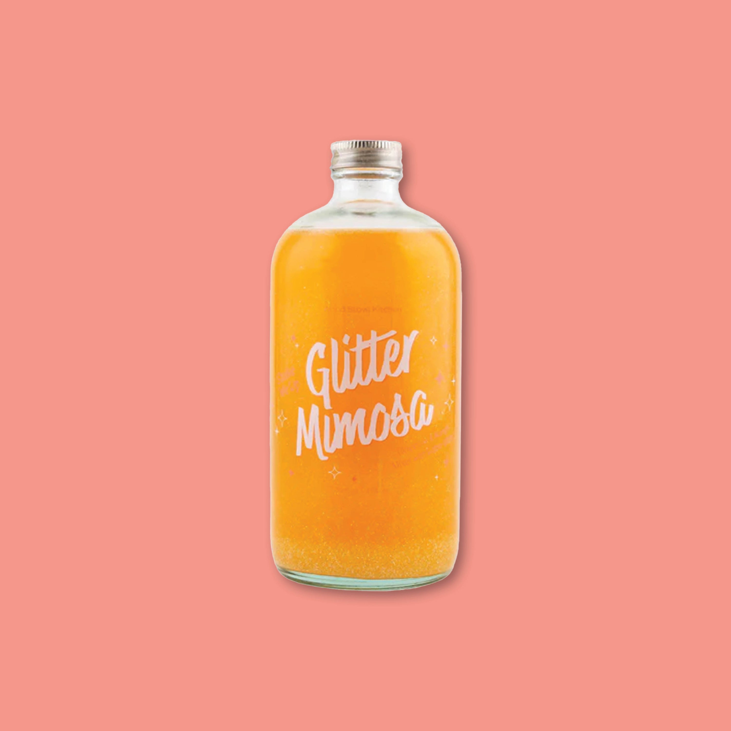On a coral background sits a 16 oz. glass bottle of Tangerine and Mango Glitter Mimosa beverage from Wood Stove Kitchen.