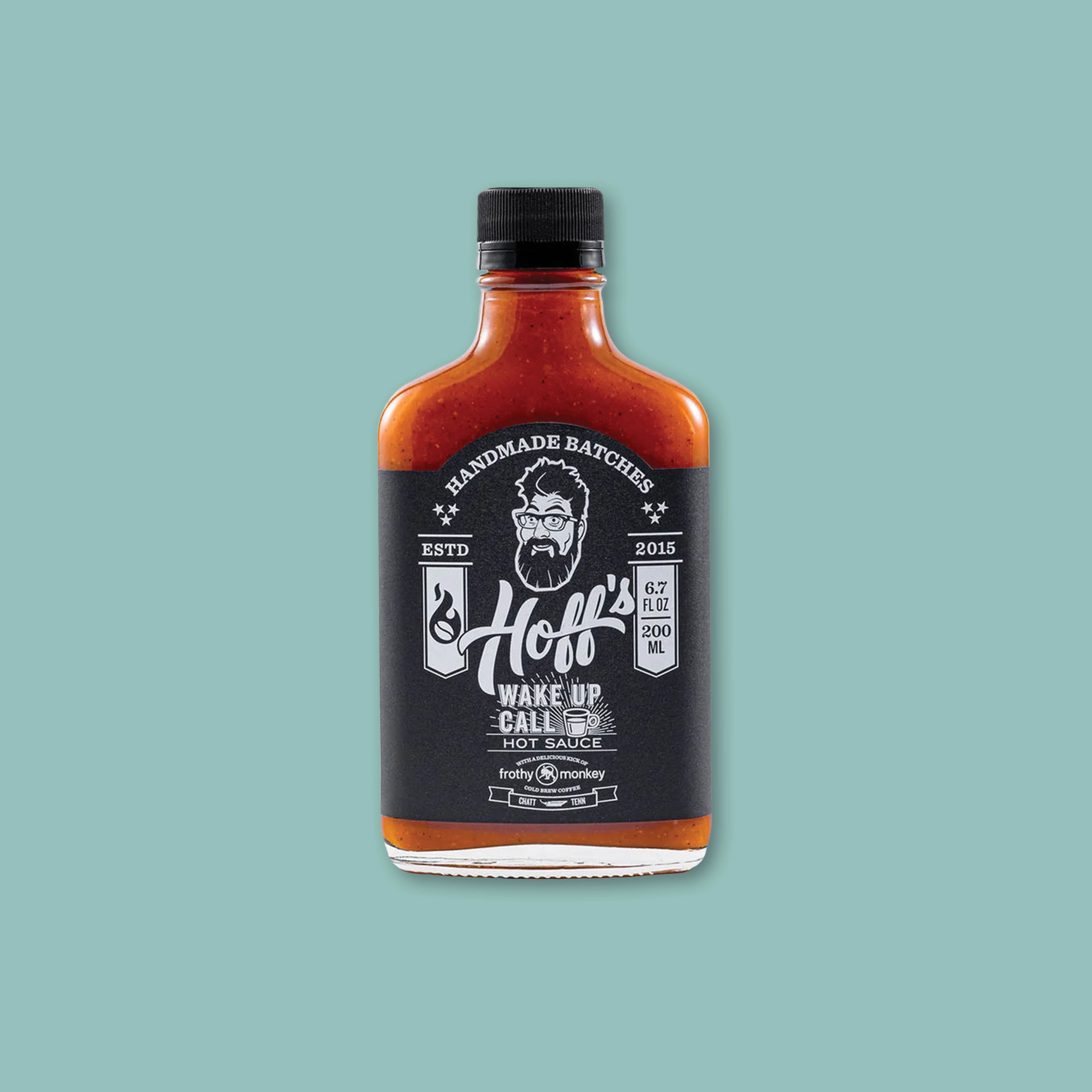 On a teal background sits a bottle of Hoff's Wake Up Call Hot Sauce with a black and white label.