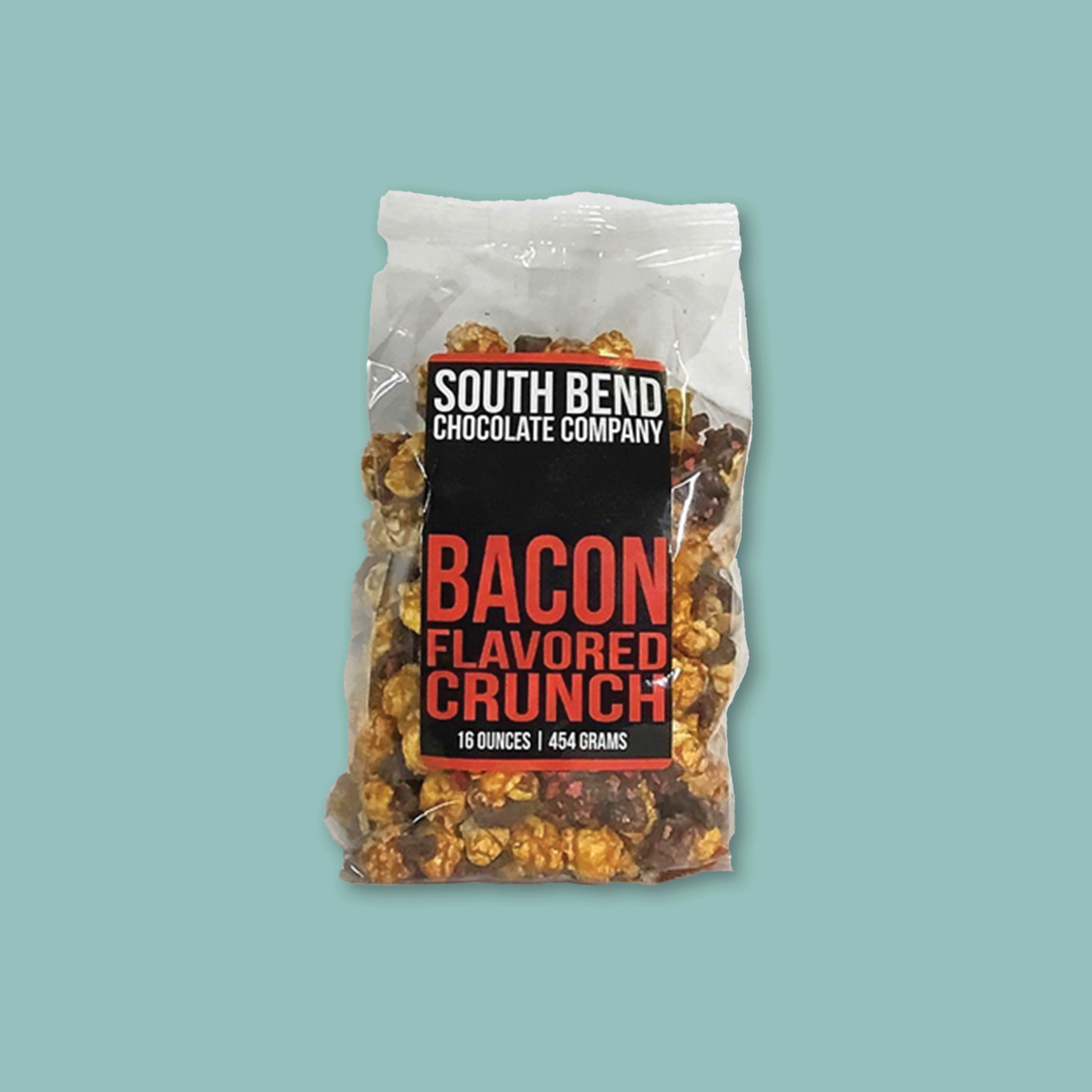 On a teal background sits a clear bag of Bacon Flavored Crunch popcorn from South Bend Chocolate Company.