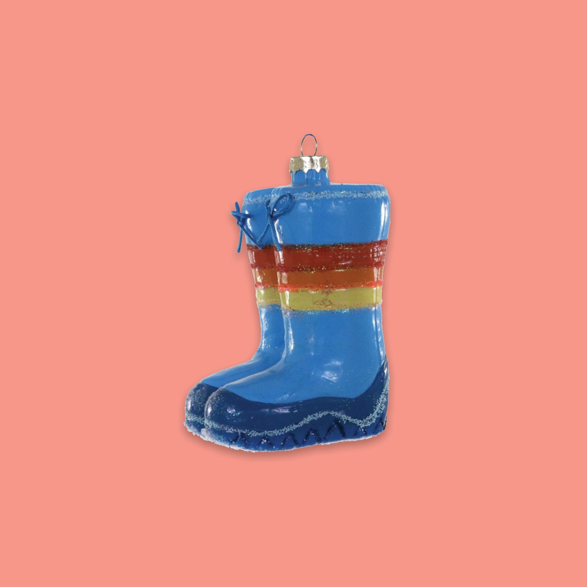 On a coral pink background sits a Rainbow Brite Moon Boots inspired glass ornament. It is in bright colors of navy, blue, yellow, orange, and red.