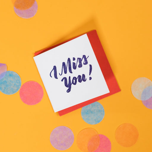 On a sunny mustard background is a mini greeting card and envelope surrounded by big, colorful confetti. The white mini card says "OMG THANK YOU!" in a coral orange handwritten serif lettering in letterpress. The envelope is a goldcolor. 2.5"x2.5"