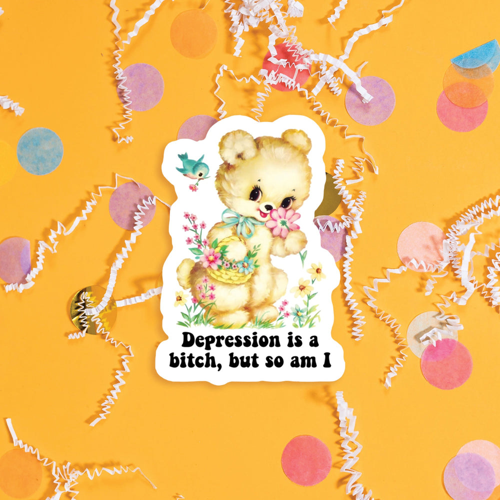 On a sunny mustard background sits a sticker with colorful confetti and white crinkle scattered around. This vintage sticker has an illustration of a darling tan bear holding a basket of flowers in one hand and smelling a flower with the other hand, and flowers and a bird. It says "Depression is a bitch, but so am I" in black, thick serif font. Approximately 3".