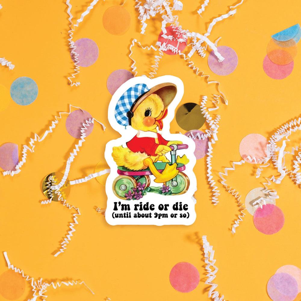 On a sunny mustard background sits a sticker with colorful confetti and white crinkle scattered around. This vintage sticker has an illustration of a cute yellow duckling riding a green and pink tricycle. It has a blue and white gingham hat on and a red jacket. It says "I'm ride or die (until about 9pm or so)" in black, handdwritten lettering. Approximately 3".