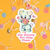 On a sunny mustard background sits a sticker with colorful confetti and white crinkle scattered around. This vintage sticker has an illustration of a cute white bear holding a bouquet of flowers. It says "Stop Stressing Over Shitty People" in bubblegum pink, handwritten script lettering. Approximately 3".