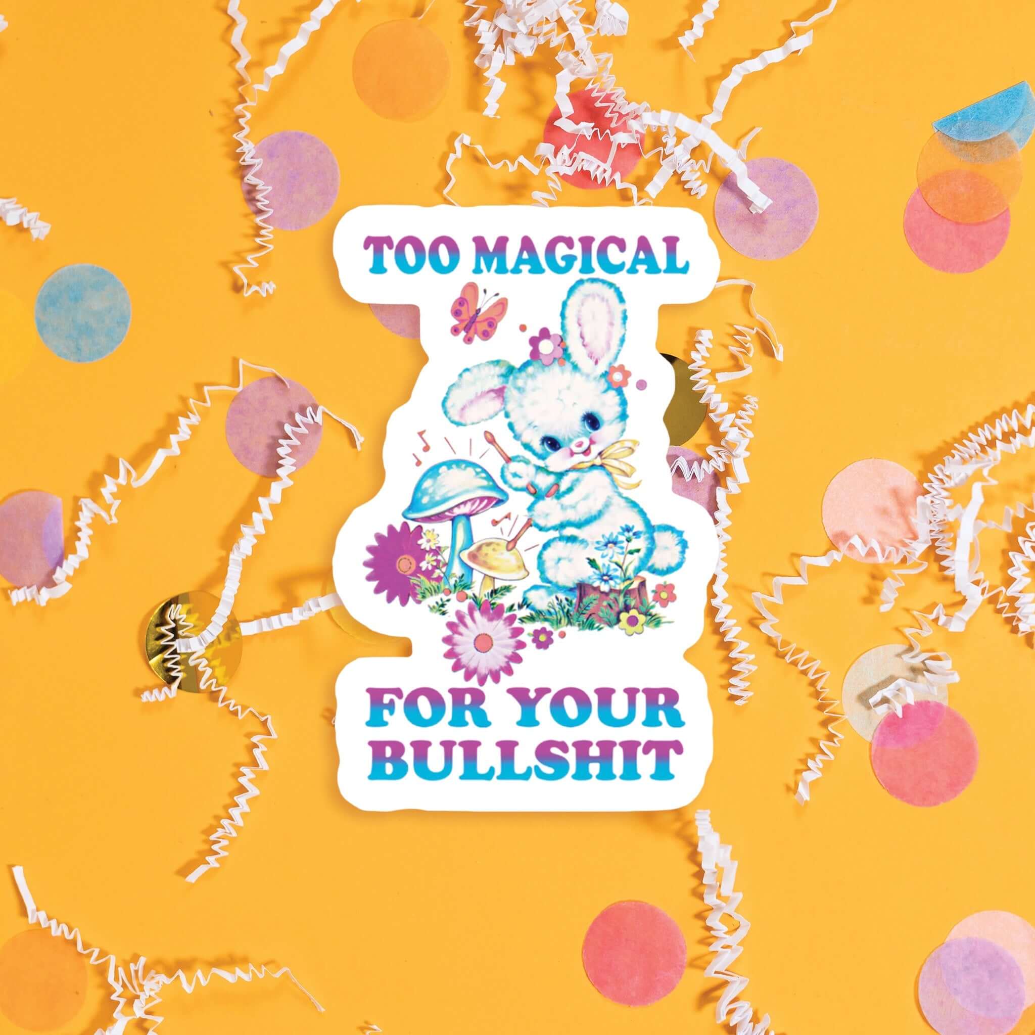 On a sunny mustard background sits a sticker with colorful confetti and white crinkle scattered around. This vintage sticker has an illustration of a cute white rabbit playing drums on mushrooms. There are flowers and a butterfly. It says "TOO MAGICAL FOR YOUR BULLSHIT" in purple and turquoise ombre, all caps thick serif font. Approximately 3".