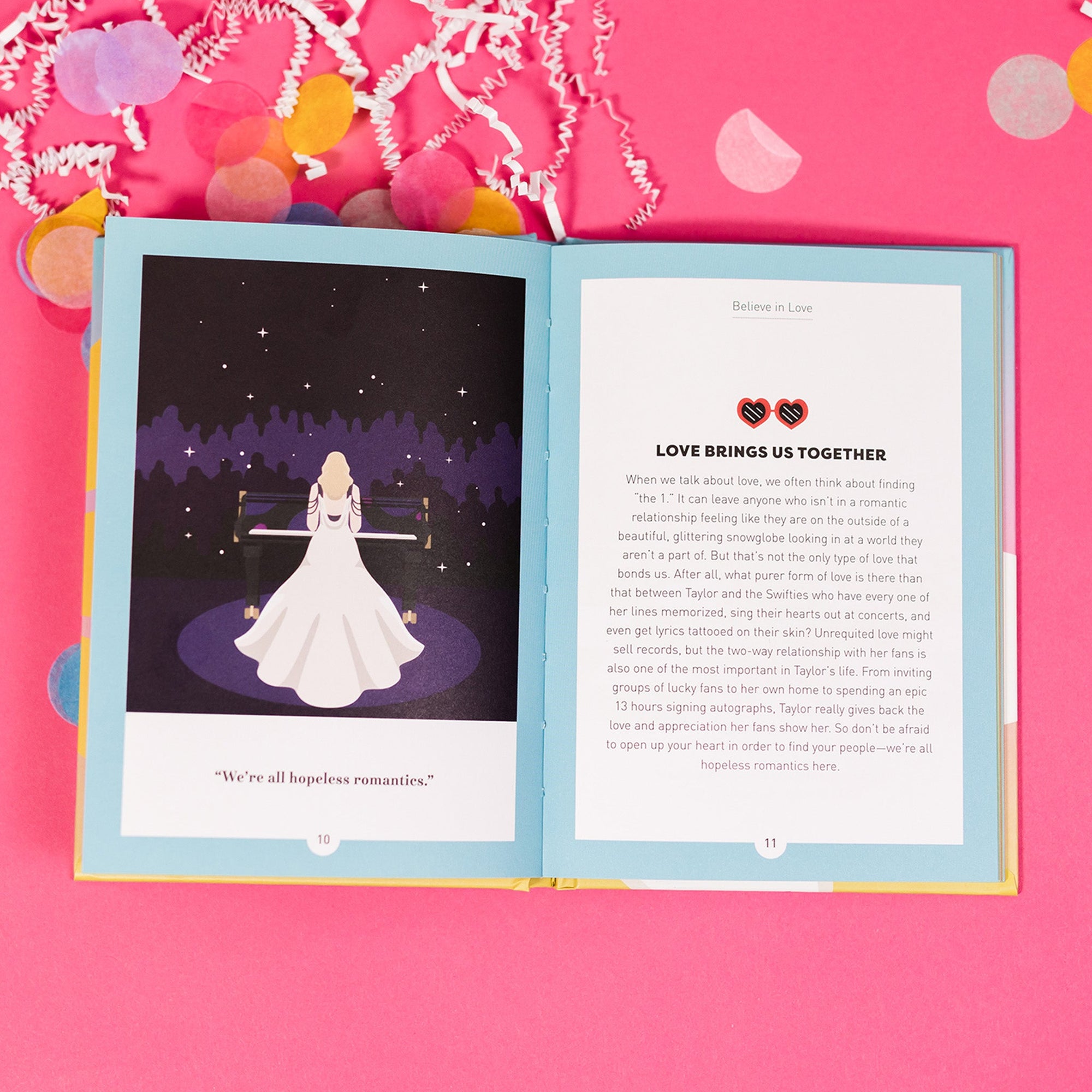 On a hot pink background sits an opened book with white crinkle and big, colorful confetti scattered around. There are mini disco balls. This Taylor Swift inspired, colorful picture book has an illustration of Taylor Swift's wearing a long white dress on the left page and it says "We're all hopeless romantics." On the right page it says "Believe in Love" with a pair of heat sunglasses and there is a paragraph titled "LOVE BRINGS US TOGETHER."