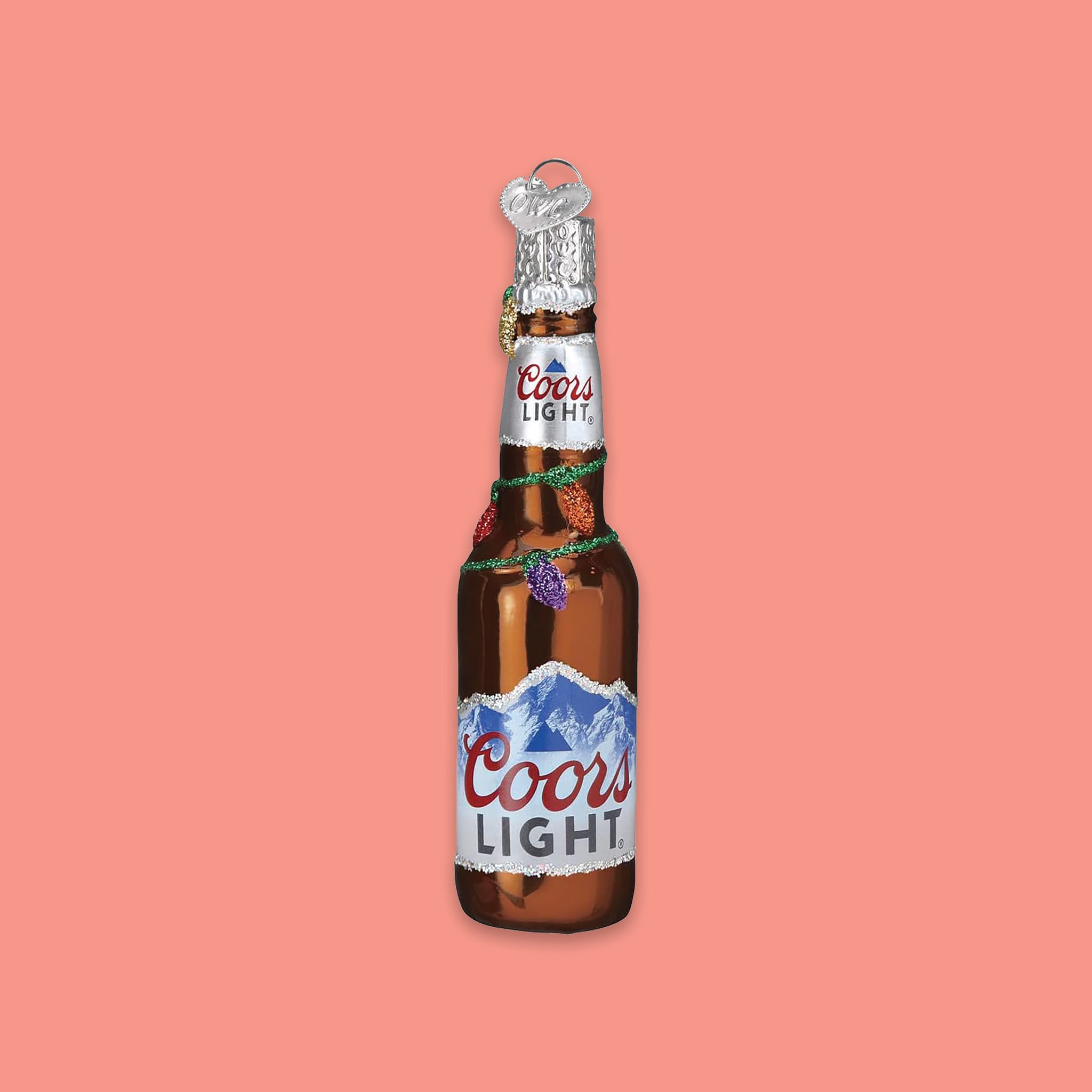 On a coral pink background sits a six pack of cans ornament. This is a glass 'Coors Light' six pack ornament.