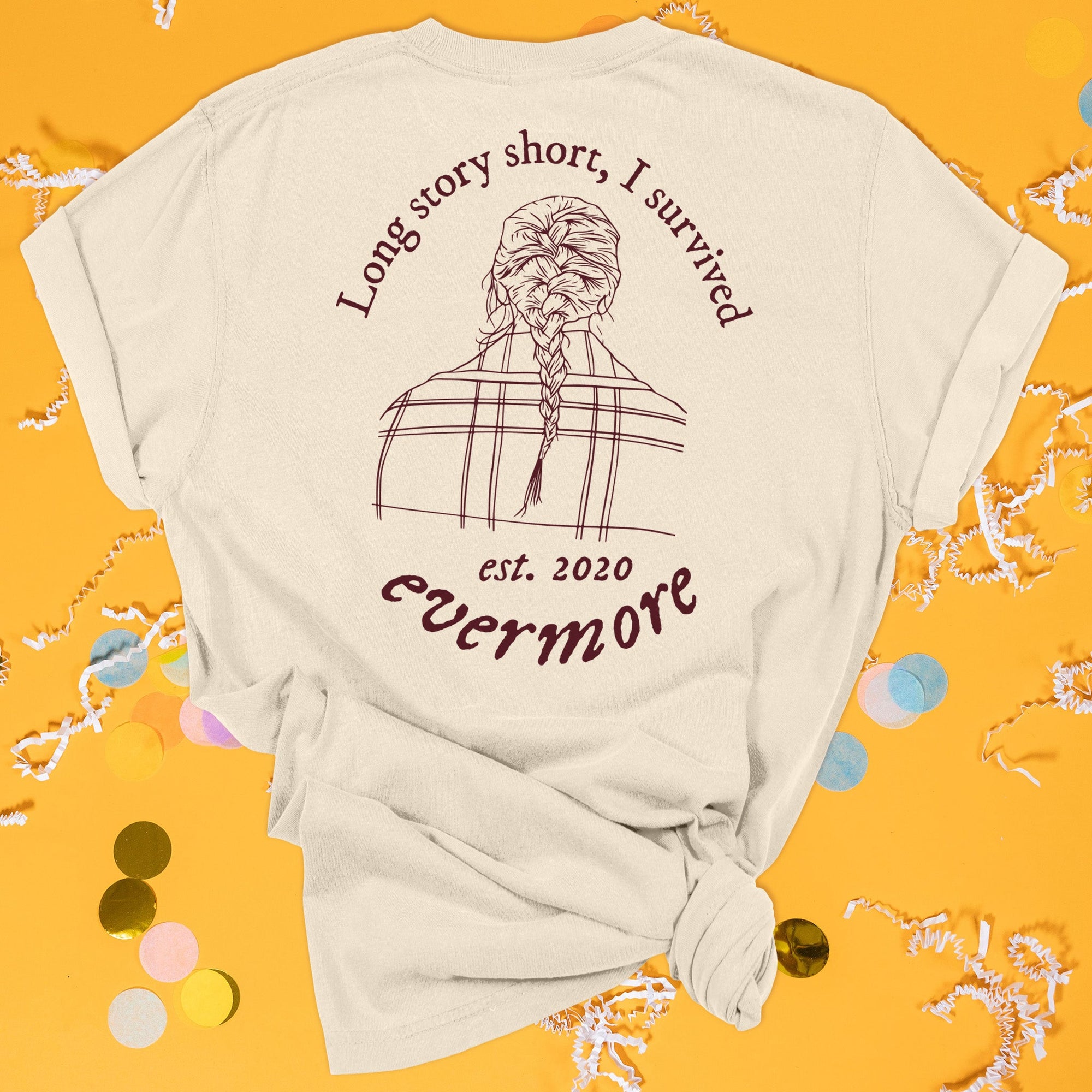On a sunny mustard background sits the back of a t-shirt with white crinkle and big, colorful confetti scattered around. This Taylor Swift Inspired Reputation tee is ivory with maroon lettering and illustration. It has an illustration of the back of a head with a french braid hair style and a plaid coat and it says "Long story short, I survived" and "evermore est. 2020."