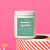 On a hot pink background sits a candle on a red and white packing tape with colorful confetti and white crinkle scattered around. It is has a mint label with white text. This Doose's Market Candle has notes of sweet creamy vanilla, fresh fruity florals, caramel, and musk & is the perfect scent for your die hard Gilmore Girls Fan! This standard sized 8 oz jar has a burn time of approximately 35+ hours, perfect for bathrooms, dressers, countertops, and nightstands.