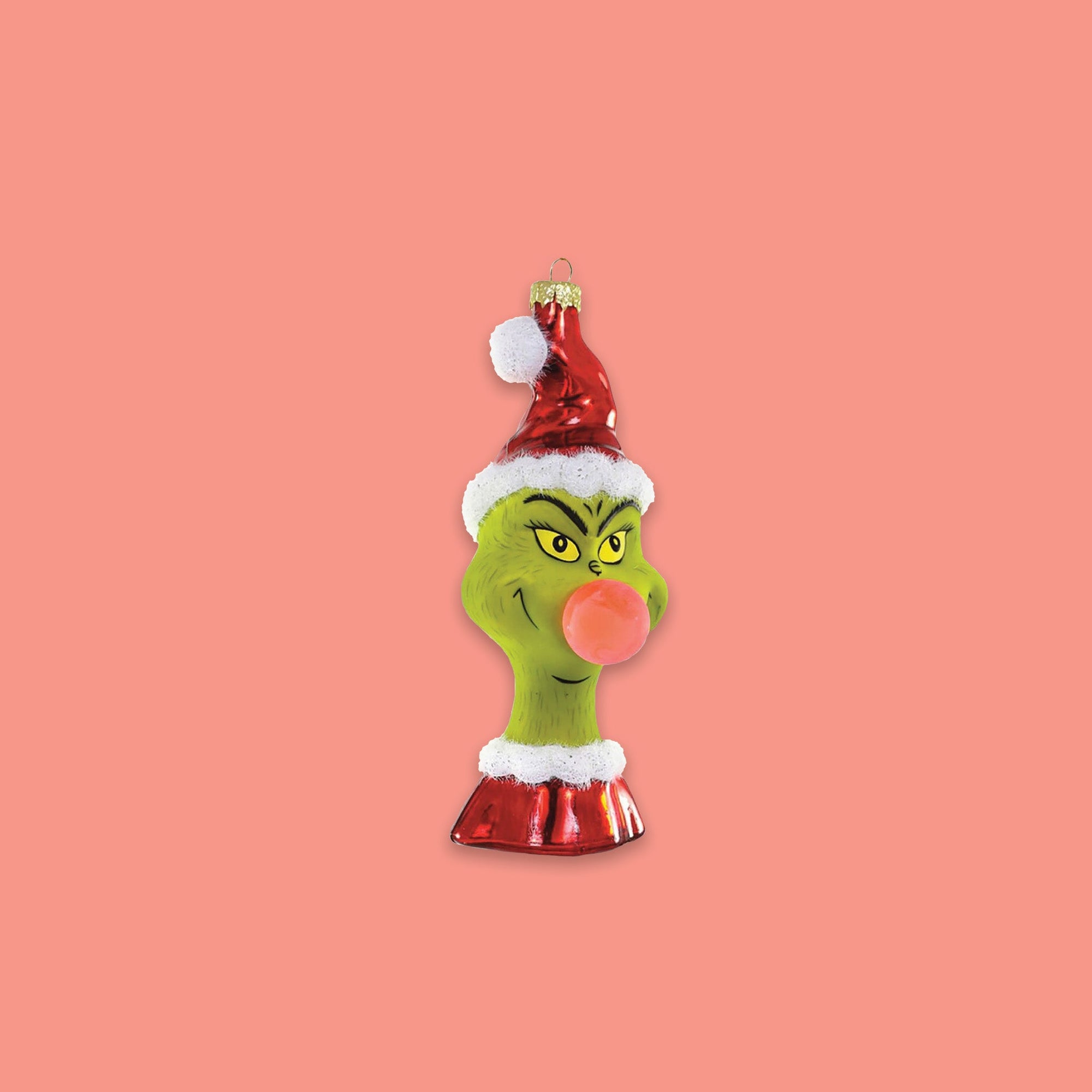 On a coral pink background sits an ornament. This Grinch ornament is a bust of Grinch wearing a santa hat and santa top and he is blowing a pink bubblegum. 