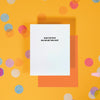 On a sunny mustard background is a greeting card and envelope with big, colorful confetti scattered around. The white greeting card says "HOW THE FUCK DID WE GET THIS OLD?" in a black, all caps block font at the top. An orange envelope sits under the card.