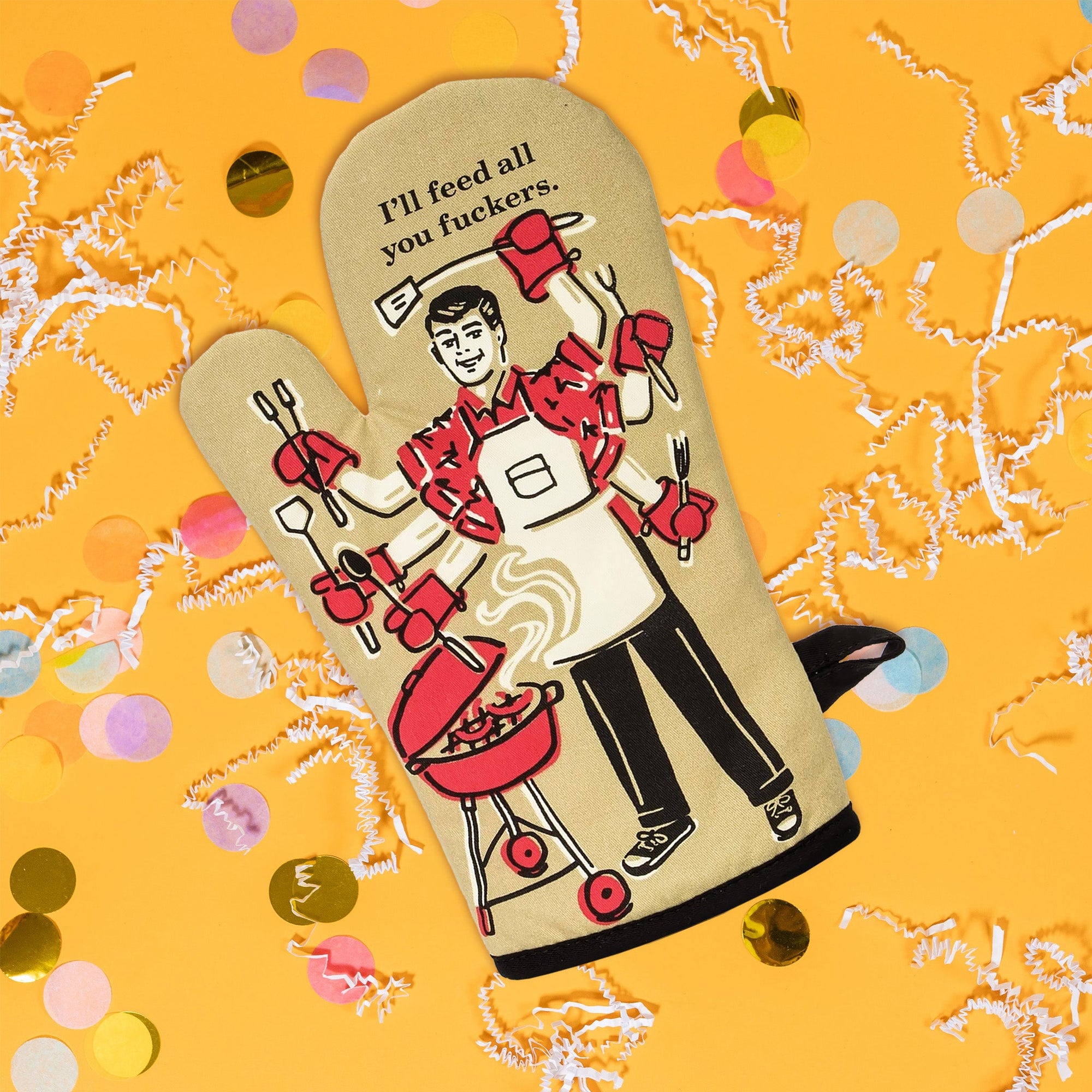On sunny mustard background sits an oven mitt with white crinkle and big, colorful confetti scattered around. The front of this khaki oven mitt has a vintage illustration of a man barbequing with six arms and hands. In each hand are bbq utensils. The colors are khaki, red, black, and white. At the top it says "I'll feed all you fuckers." in black serif font.