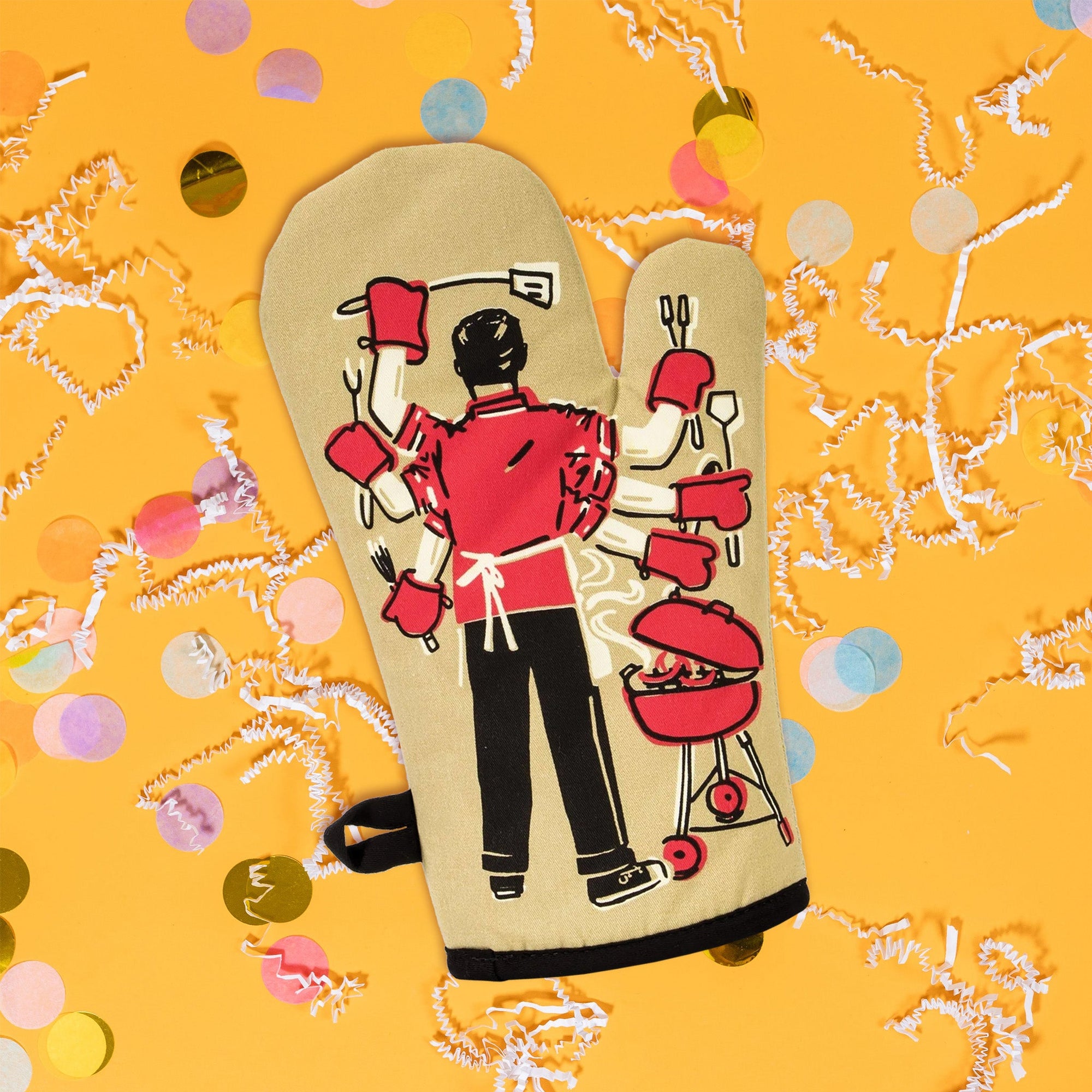 On sunny mustard background sits an oven mitt with white crinkle and big, colorful confetti scattered around. The back of this khaki oven mitt has a vintage illustration of the back of a man barbequing with six arms and hands. In each hand are bbq utensils. The colors are khaki, red, black, and white.