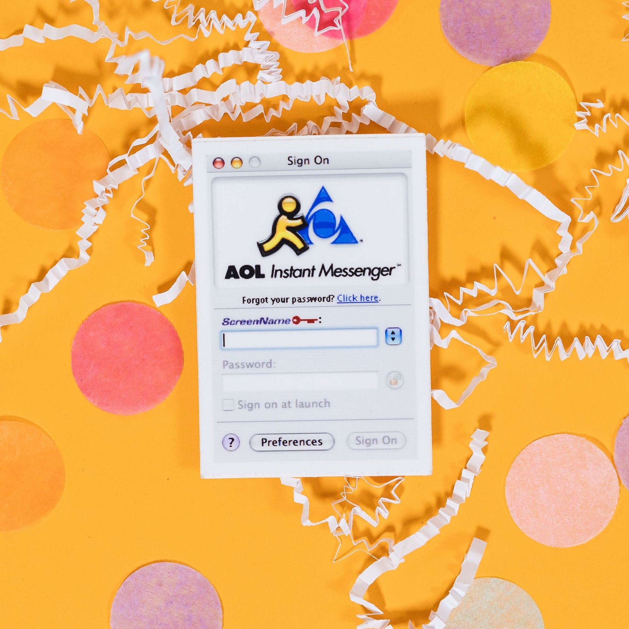 On a sunny mustard background sits a sticker with white crinkle and big, colorful confetti scattered around. This white, rectangle sticker has an illustration of AOL Instant Messenger logo in yello, black and blue at the top and says "Sign On", "AOL Instant Messenger", "Forgot your password? Click here. (underlined)," "ScreenName (with a red key next to it)," "Password:," "Sign on at Launch (with a square in front of it),", "? (in a lavender circle)," "Preferences," "Sign On."