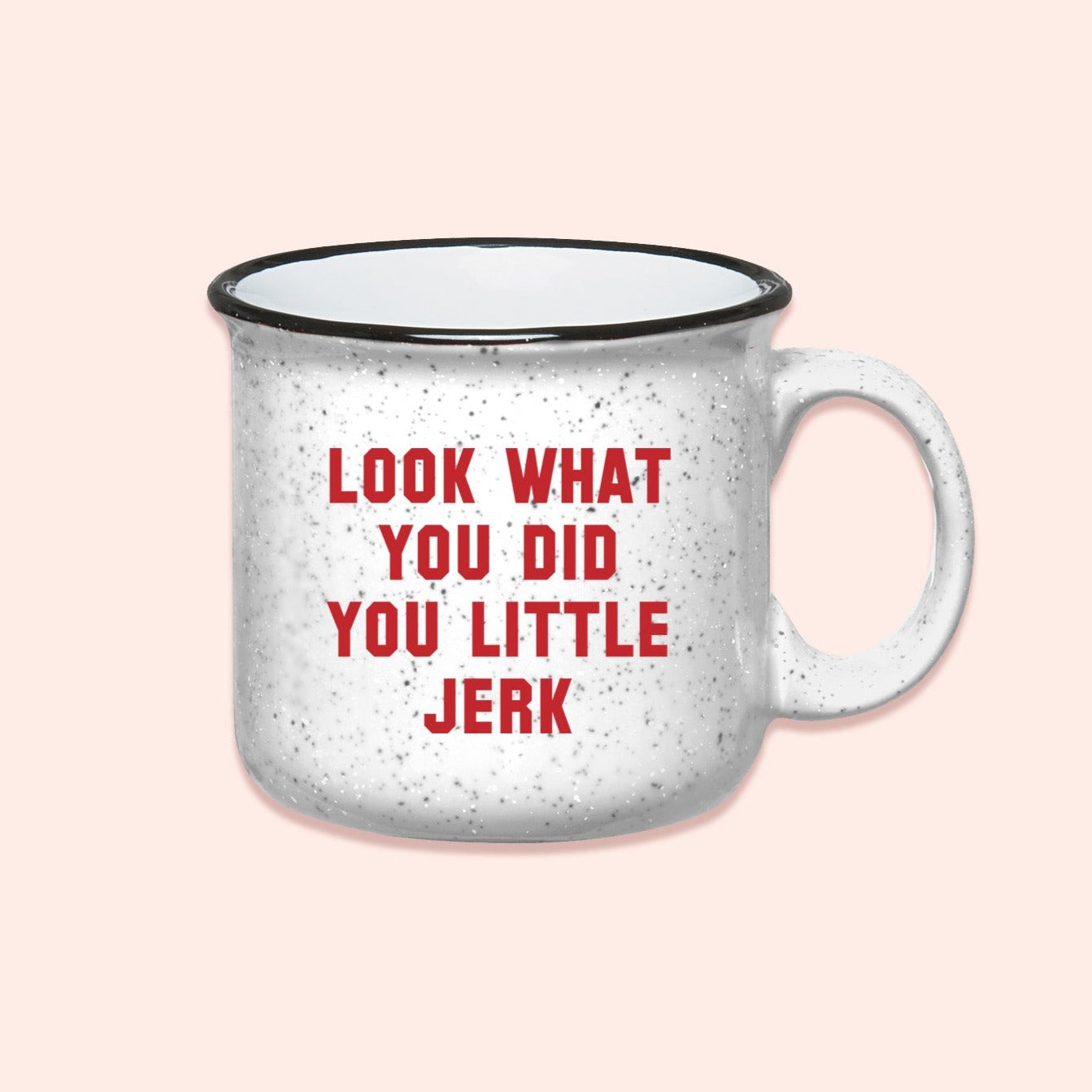 On a light pink background sits a campfire mug. This Home Alone inspired mug is white with black specks and it says in red lettering "LOOK WHAT YOU DID YOU LITTLE JERK."