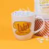 On a sunny mustard background sits a mug with white crinkle in it. This Gilmore Girls inspired mug has an illustration of Luke's Gilmore Girls coffee mug in colors of sunny mustard, orangey-red, and black.