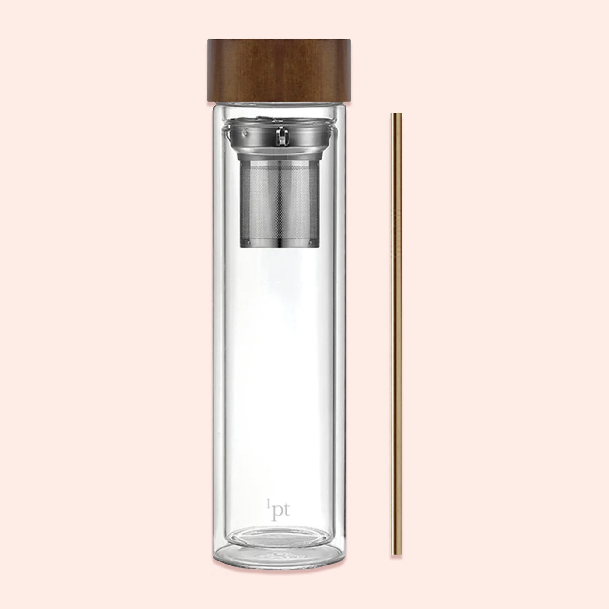 On a light pink background sits an infusion bottle with a wood lid. It has a gold straw next to it.