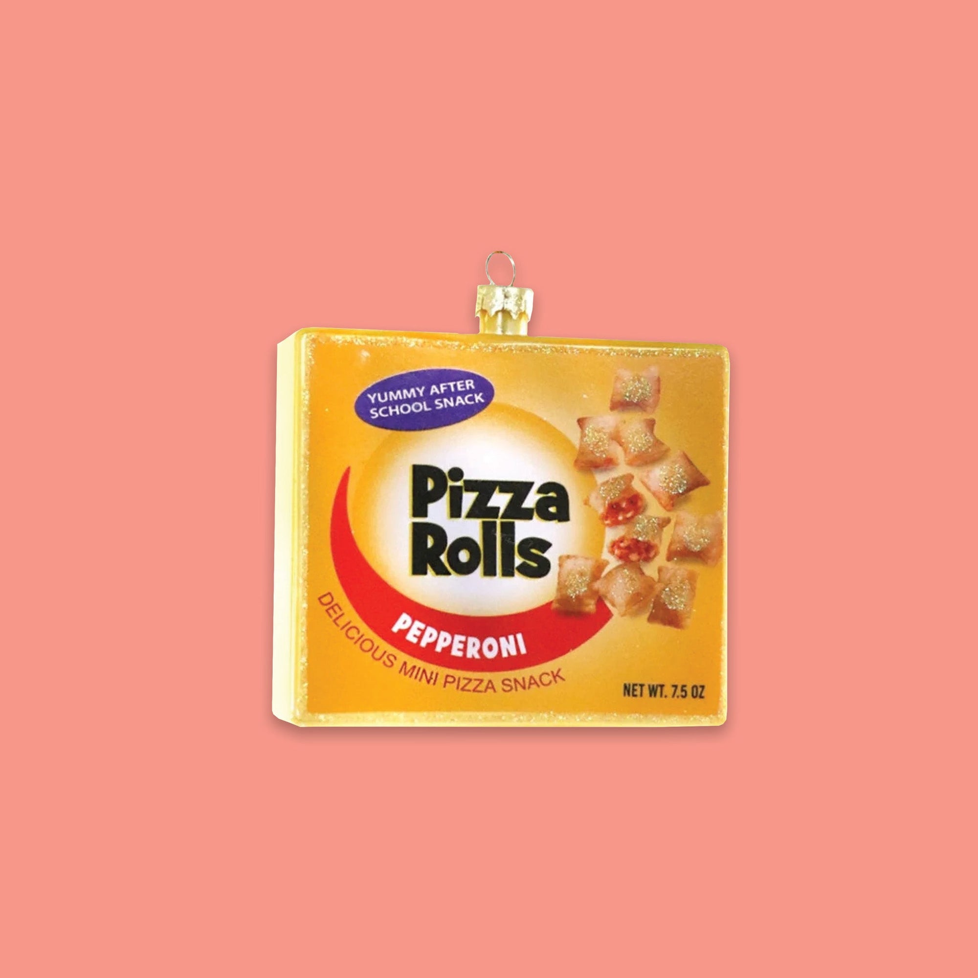 On a coral pink background sits a box ornament. This 'Pizza Rolls' glass box ornament is yellow with red and has pizza rolls on the front. It says "YUMMY AFTER SCHOOL SNACK" and "PEPPERONI DELICIOUS MINI PIZZA SNACK."