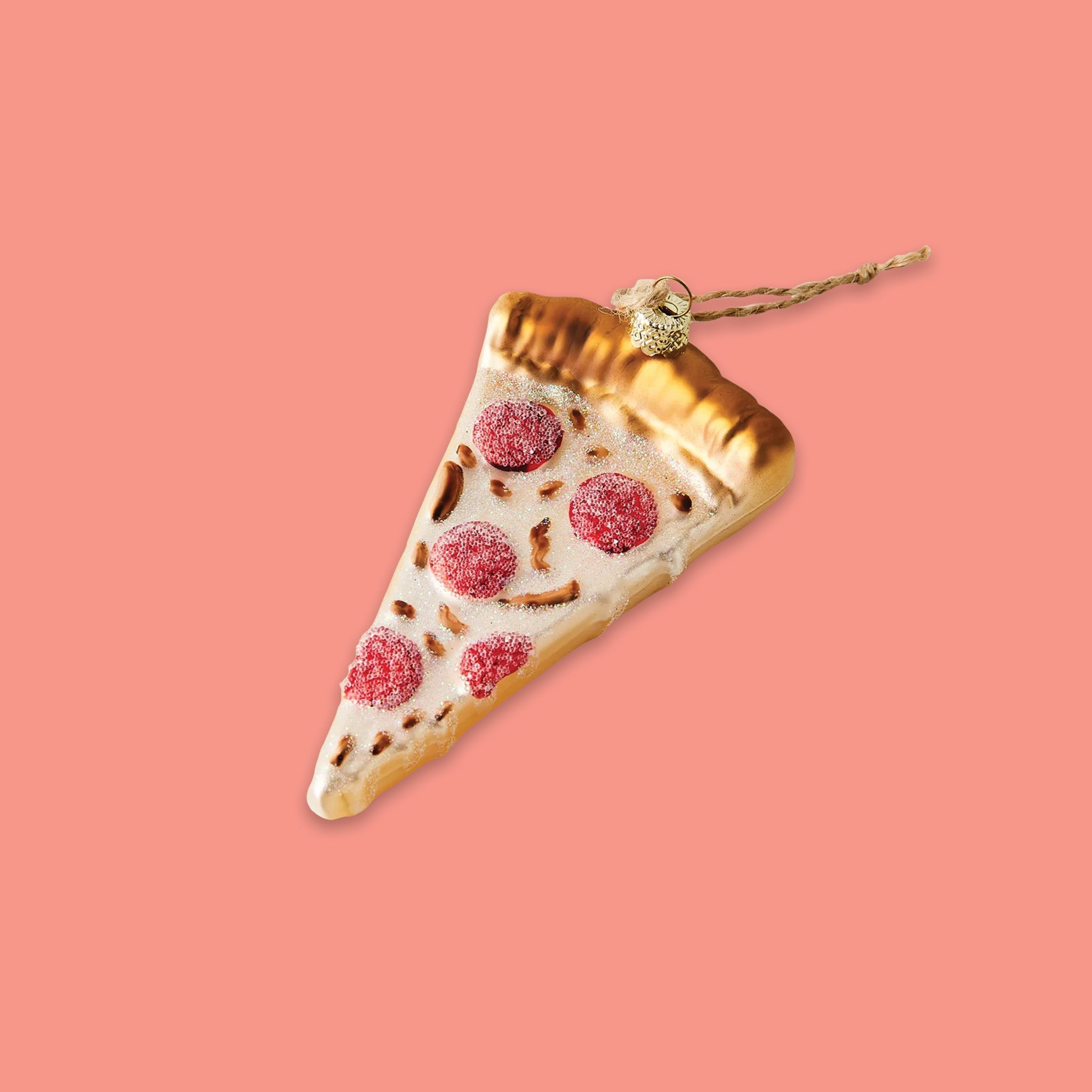 On a coral pink background sits a box ornament. This pizza slice glass ornament is has a golden brown crust, crispy pepperoni, and melted cheese.