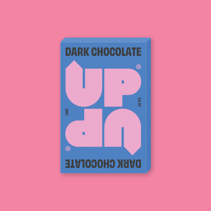 On a bubblegum pink background sits a box of UP UP Dark Chocolate. The packaging is in blue, lavender, and black. 130G 4.6 OZ