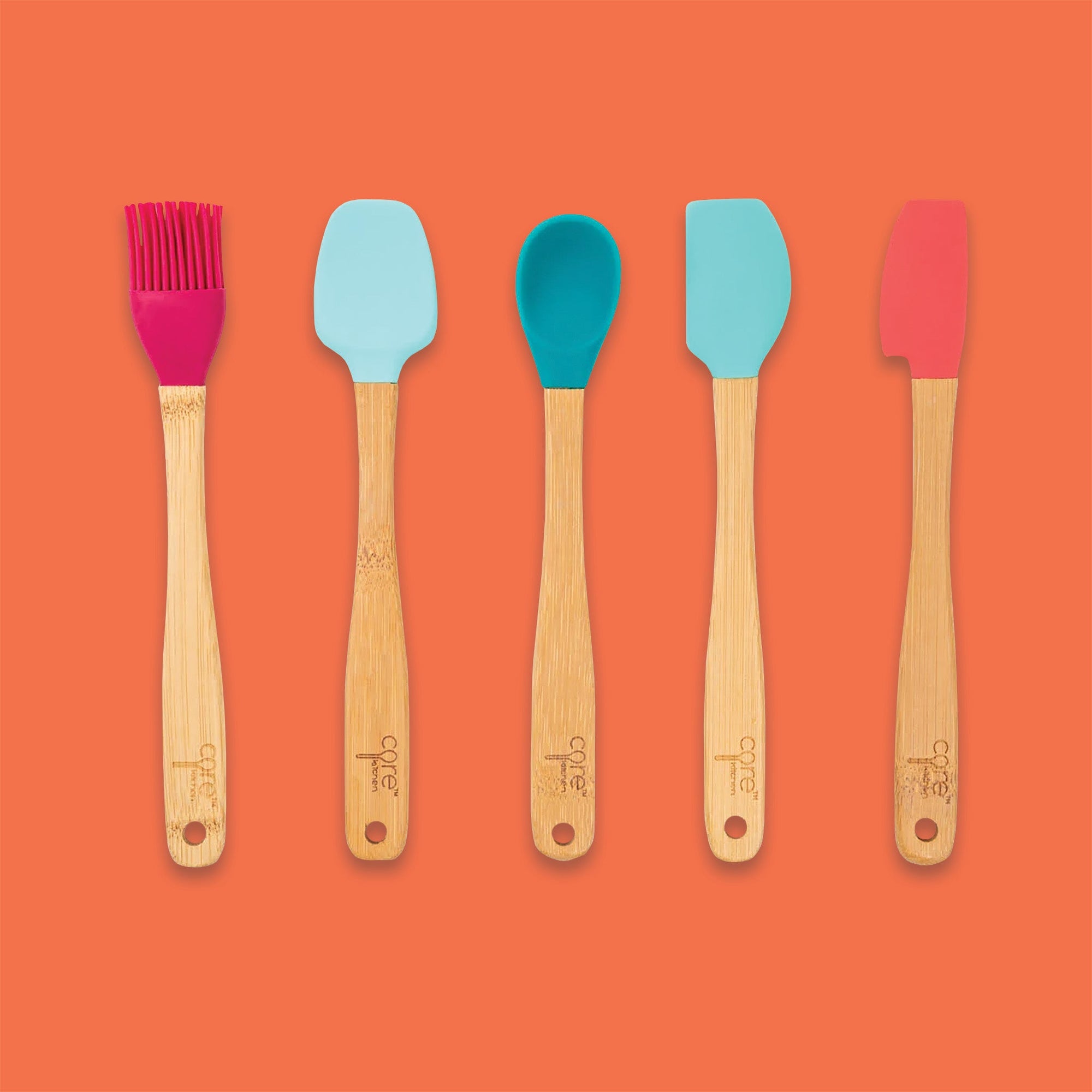 On an orangey background sits a set of five mini utensils. These mini utensils are made of bamboo and silicone. The silicones are in different colors of red-pink, light blue, teal, light teal, and coral.