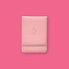 On a hot pink background sits a notebook. This light pink vegan leather, pocket journal has a middle finger in gold foil.