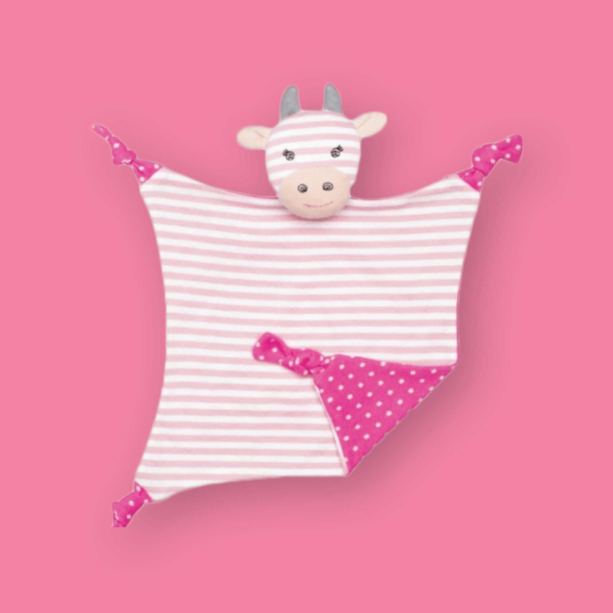 On a bubblegum pink background sits an Organic Farm Buddy pink striped cuddly cow for newborns. It has light pink and white stripes on the front and on the back is hot pink with white polka dots. 