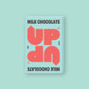 On a mint green background sits a box of UP UP Milk Chocolate. The packaging is in mint green and orangey-red.