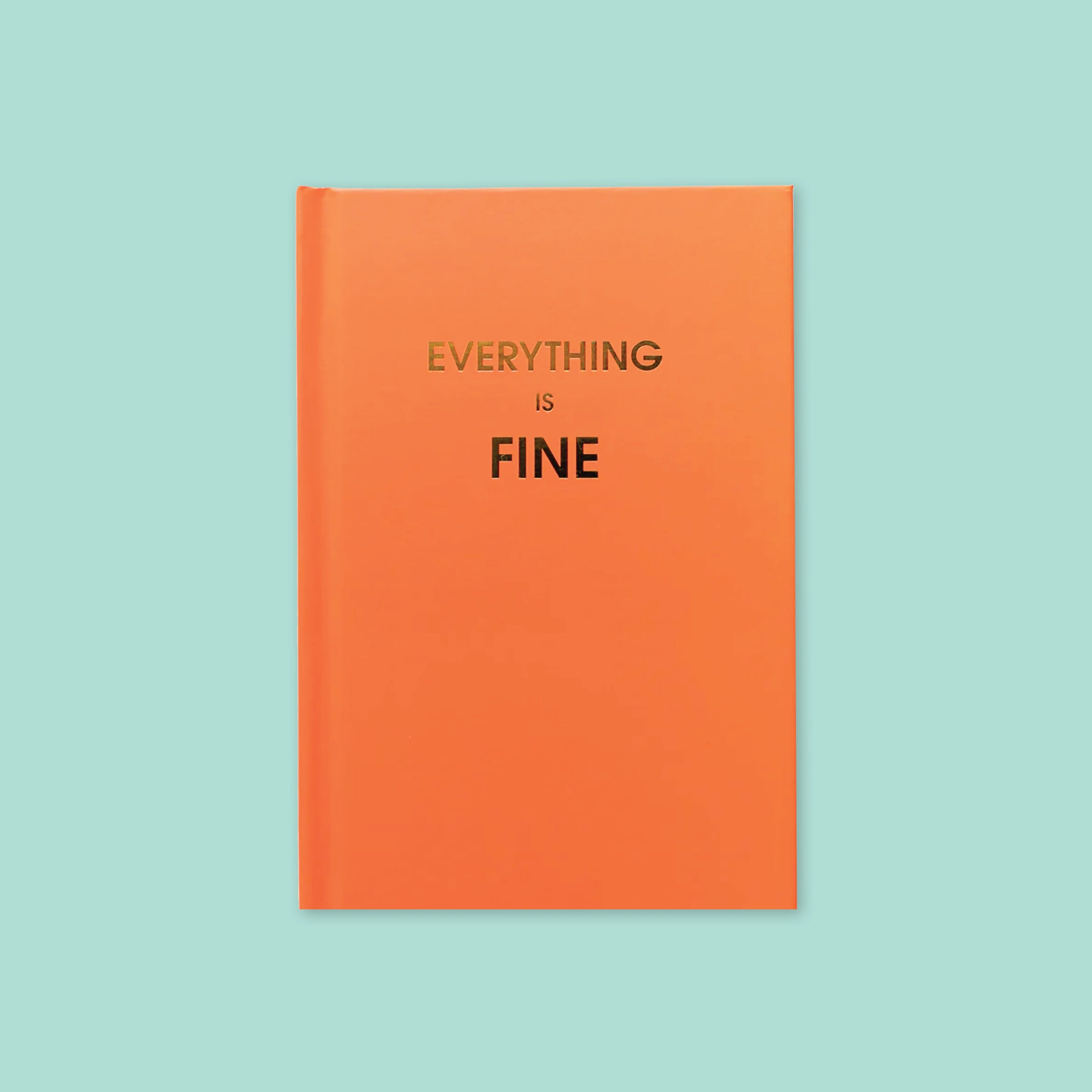 On a mint background sits a book. This orange journal says "EVERYTHING IS FINE" in gold, all caps block font.