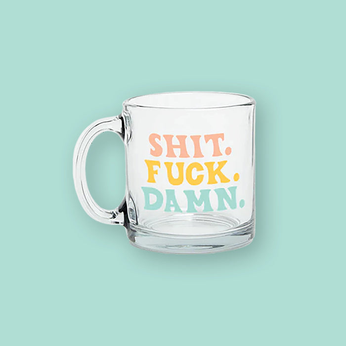 On a mint green background sits a clear mug. It says "SHIT." in peach, all caps handwritten lettering, "FUCK." in sunny mustard, all caps handwritten lettering, and "DAMN." in mint, all caps handwritten lettering. 