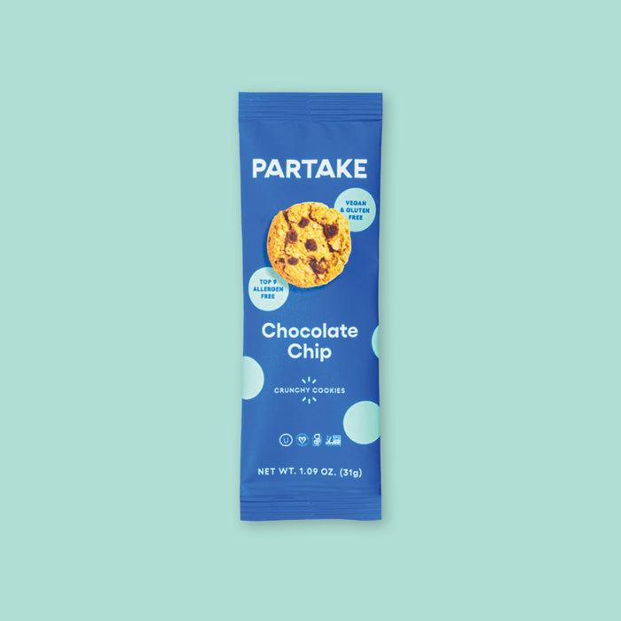 On a mint green background sits a package. This blue package has a picture of a cookie with chocolate chips on it and there are mint dots around it. It says "PARTAKE Chocolate Chip" in white, block font. It also says "CRUNCHY COOKIES" in white, all caps block font. NET WT. 1.09 OZ. (31g)