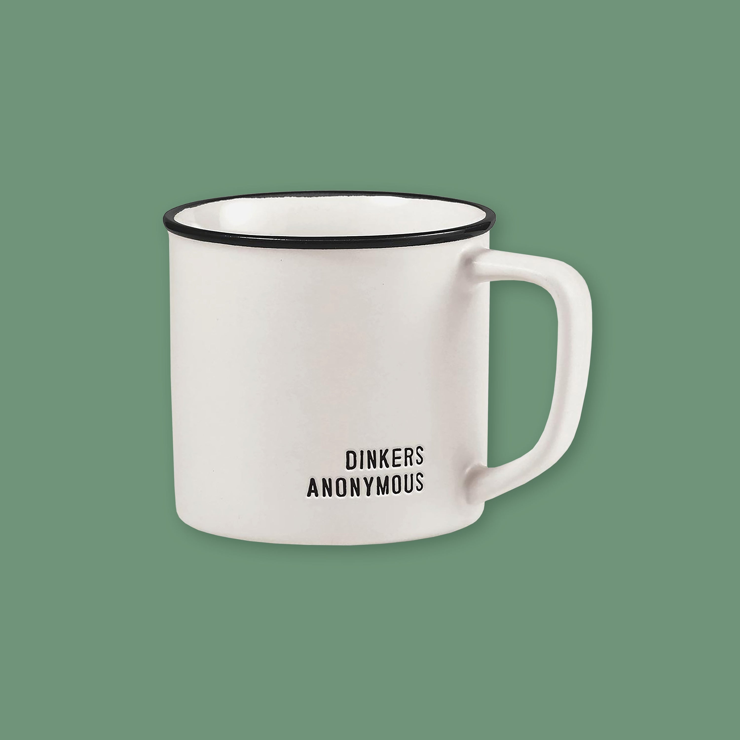 On a moss green background sits a mug. This white mug has a black rim and it says on the bottom right "DINKERS ANONYMOUS" in black, all caps block lettering.