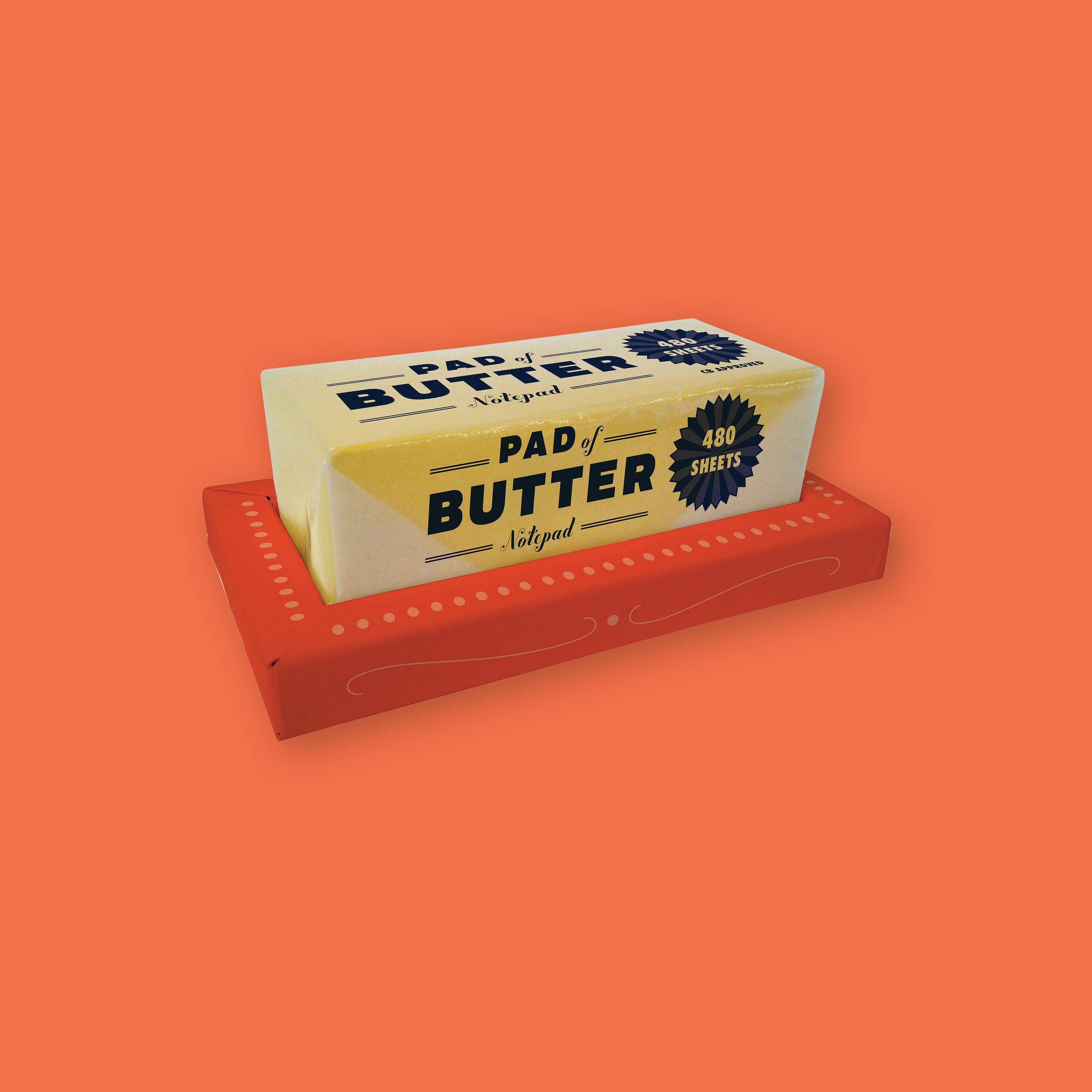 On an orangey-red background sits a package that looks like a stick of butter on a red tray. It is a "PAD of BUTTER Notepad" in navy font. It is 480 sheets notepad that is wrapped in a clear sheet to resemble a wrapped stick of butter. 