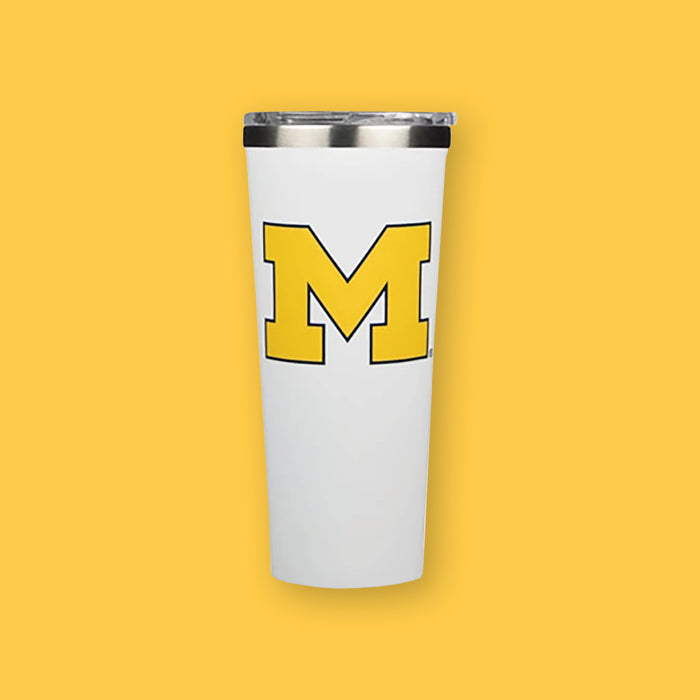 On a sunny mustard background sits a white Corkcicle Michigan Wolverines tumbler. It has a yellow and blue collegiate letter "M" on the front. 24oz