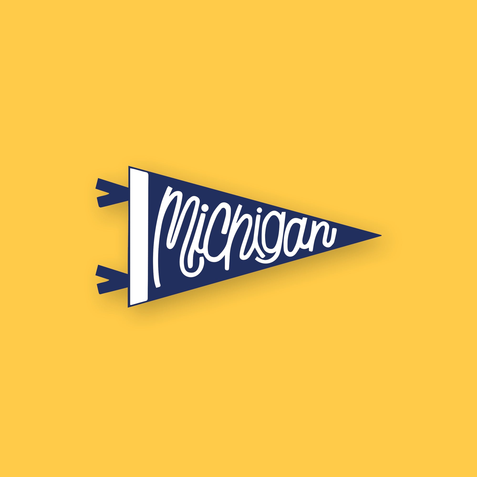 On a sunny mustard background sits an RPS Exclusive pennant magnet. It is navy with white, handwritten lettering that says "Michigan." 