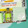 On a cool green and blue wavy background sits a wooden tray of gifts on white paper krinkle. This photo is a close-up on the mini bottle of Cheeky Lime Juice for cocktails, and a Patchology Chill Mode soothing cannabis oil under eye gel patches. Both have light green in the packaging and look cute together.
