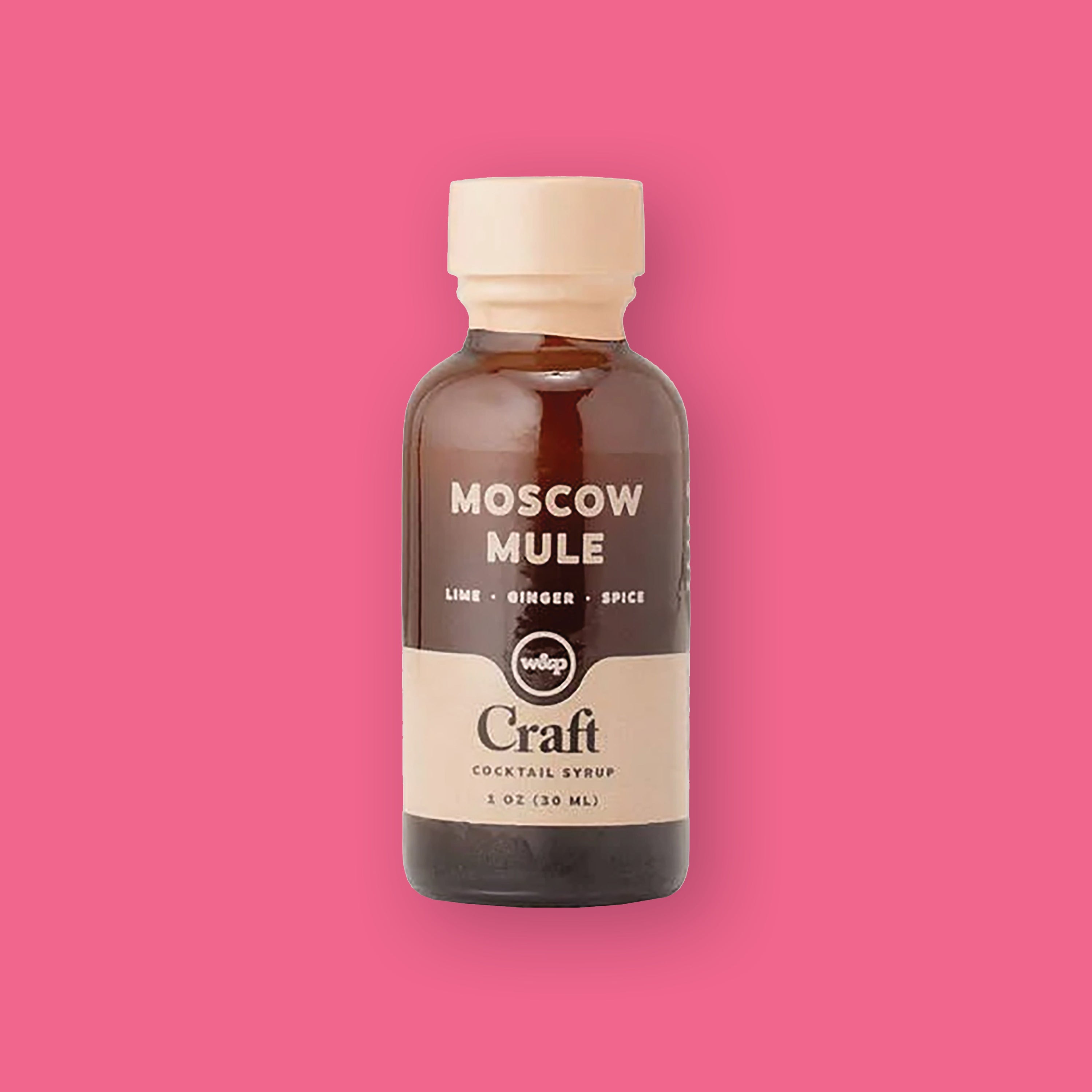 On a hot pink background sits a bottle. This brown glass bottle has a cream top and a wide stripe at the bottom. It says in cream "MOSCOW MULE" in all caps, block font. Under it says "LIME • GINGER • SPICE" in cream, all caps block font. It is "Craft COCKTAIL SYRUP" by w&p. 1 OZ (30 ML)