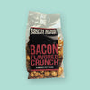 On a mint green background sits a package. This clear package is filled with caramel popcorn and has a black label. It says "SOUTH BEND CHOCOLATE COMPANY" in white, all caps block font. It says "BACON FLAVORED CRUNCH" in a maroon, all caps block font. 8 ounces | 227 grams