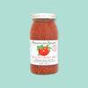On a mint green background sits a jar. The clear jar has a white lid and label with an illustration of a tomato with leaves. It says "American Spoon" in black, serif font. Under the tomato it says "BLOODY MARY MIX" in red, all caps serif font. It also says "A Midwestern twist on a classic, with hand-grated horseradish and aromatic dill." in black, serif font. 25.5 fl oz • 754 mL