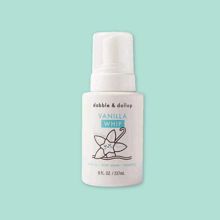 On a mint green background sits a white bottle with white cap. It has an illustration of a vanilla leaf in black. It says "dabble & dollop" in black, block font. In turquoise it says "VANILLA WHIP," "tear free!," "BUBBLES • BODY WASH • SHAMPOO." 8 FL. OZ. / 237mL