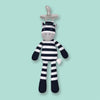 On a mint green background sits a black and grey snuggly buddy. It is an Organic Farms Buddies eco-friendly plush pacifier striped cow.