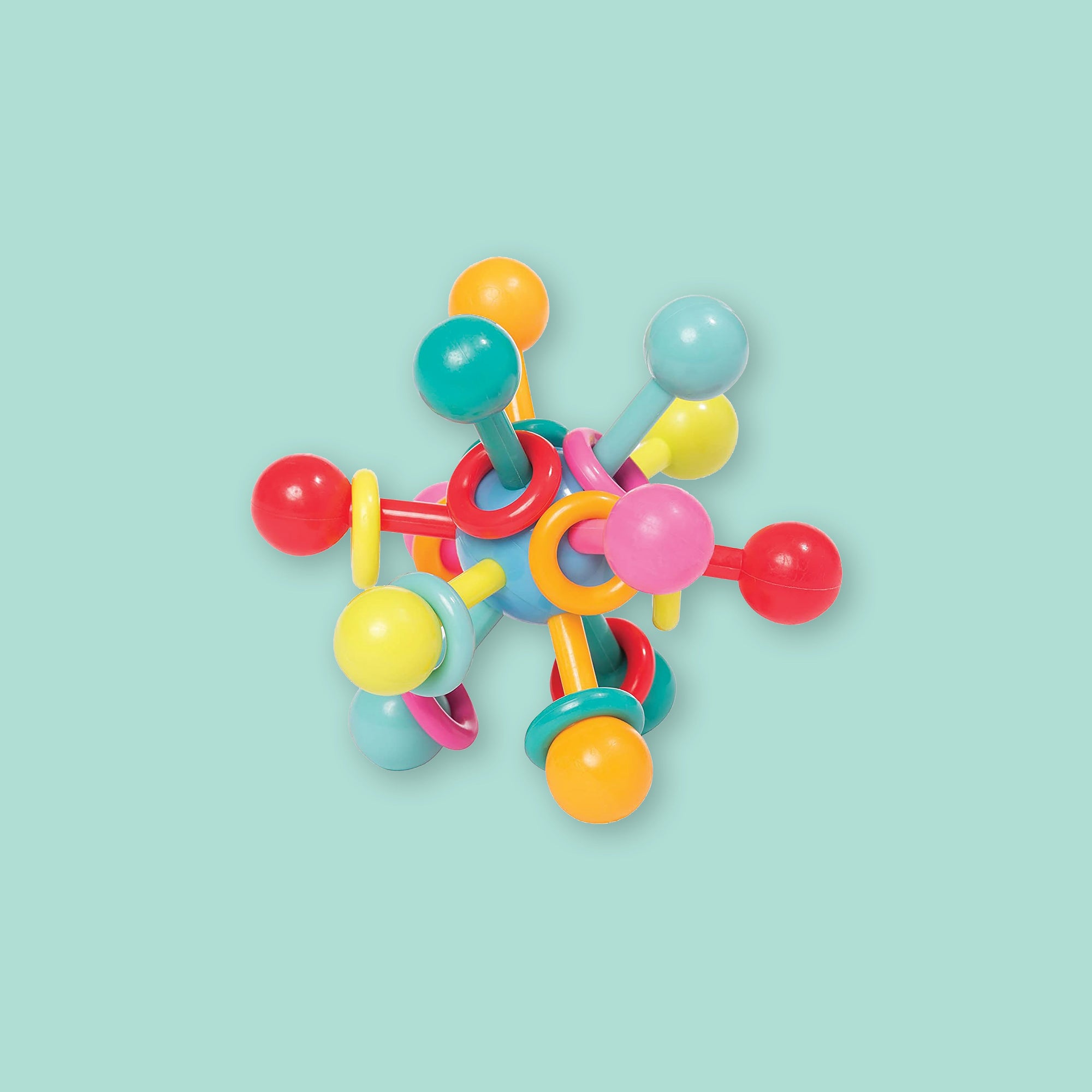 On a mint green background sits a colorful atom teether. It is in the shape of an atom and has all different colors.  