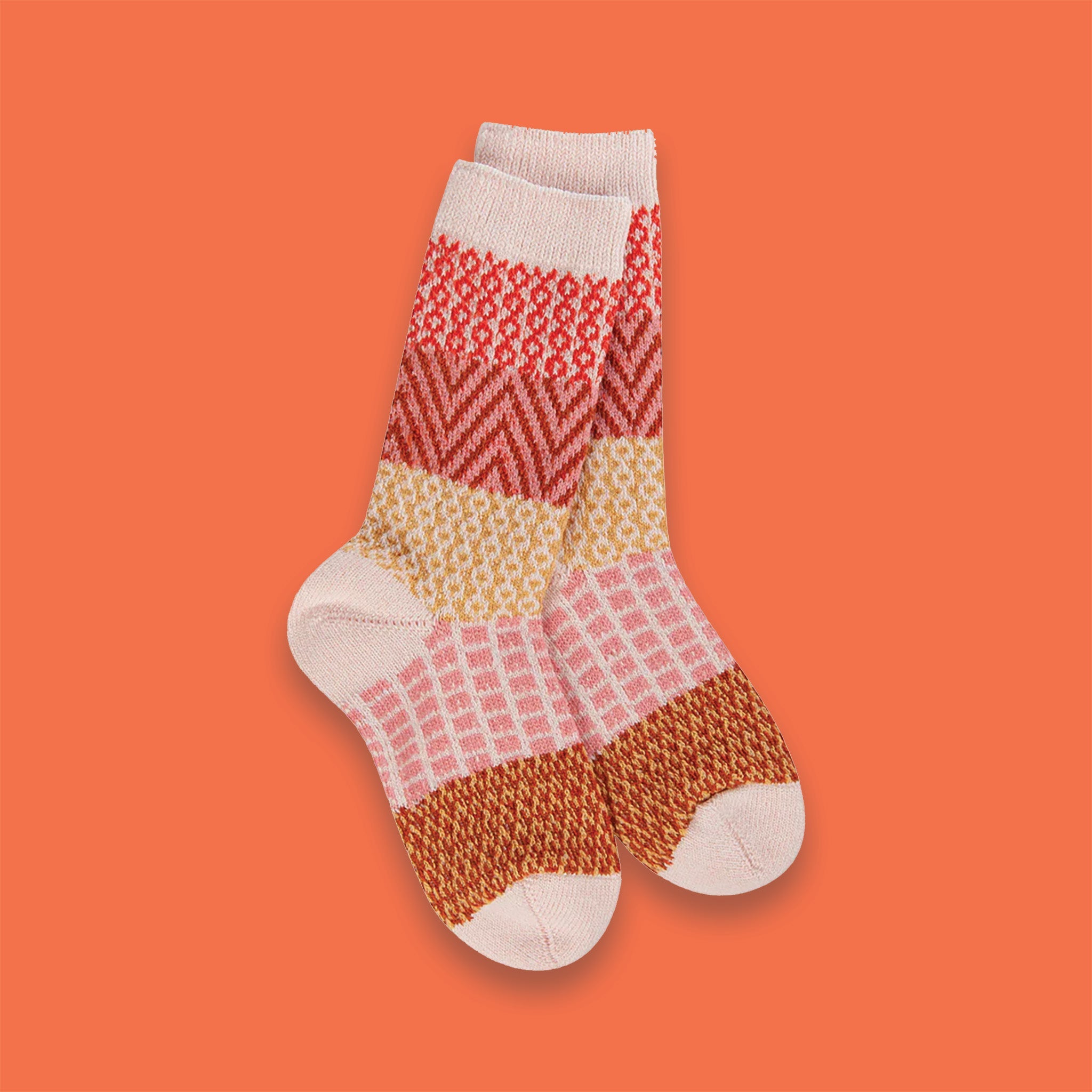 On an orange background sits the world's softest socks with different patterns in modern fall colors, including orangey-red, rust, peach, and mustard. 