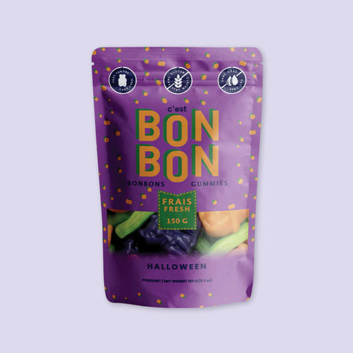 On a lavender background sits a bag of C'est Bon Bon artisanal gummy candies in a purple Halloween bag.