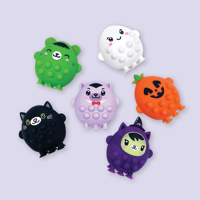 On a lavender background sits an assortment of six pop fidgets in a Halloween theme, including a green zombie, white ghost, black cat, orange pumpkin and more!